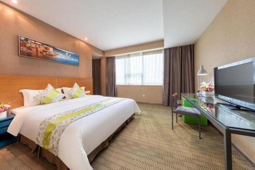 a hotel room with a large bed and a flat screen tv at Catic Hotel--Adjacent Buliding in Zhuhai