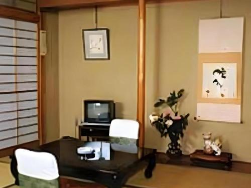 a living room with a table and chairs and a television at Kakeyu Onsen Hotel Kameya in Ueda