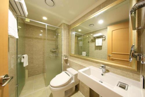a bathroom with a toilet and a sink and a mirror at Jeju Booyoung Hotel in Seogwipo