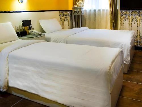 two beds in a hotel room with white sheets at Happy Family Hotel in Macau