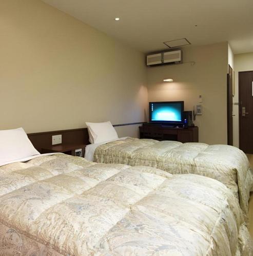 two beds in a room with a flat screen tv at Hakata Yufuin Takeo Onsen Manyo no Yu in Fukuoka