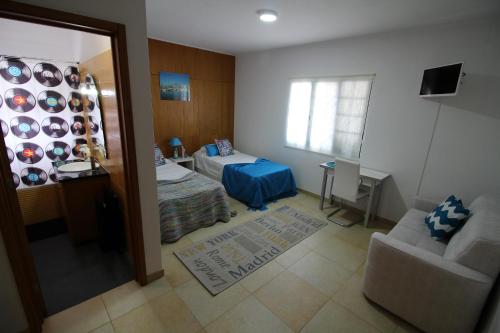 a bedroom with a bed and a couch and a window at Vivenda Atlântida in Ponta Delgada