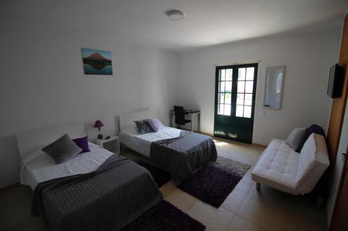 una camera con due letti, un divano e una sedia di Vivenda Atlântida a Ponta Delgada