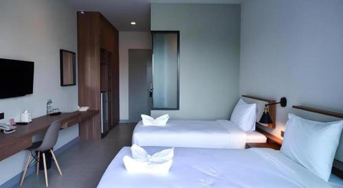 a hotel room with two beds and a desk and a television at @Sleep in Nakhon Pathom