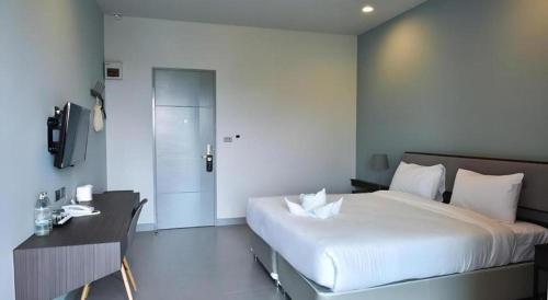 a bedroom with a large white bed and a desk at @Sleep in Nakhon Pathom