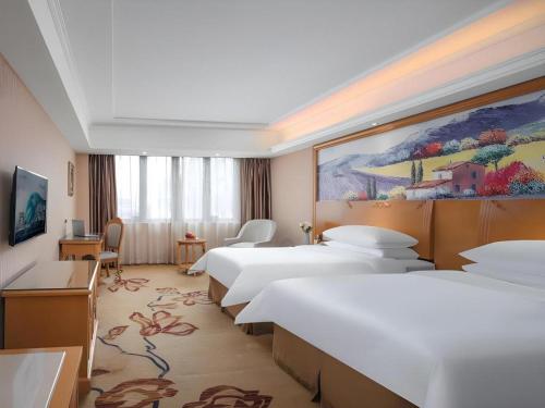 una habitación de hotel con 4 camas y un cuadro en la pared en Vienna 3 Best Hotel Jiangsu Suzhou Zhouzhuang Luzhi Ancient Town, en Suzhou