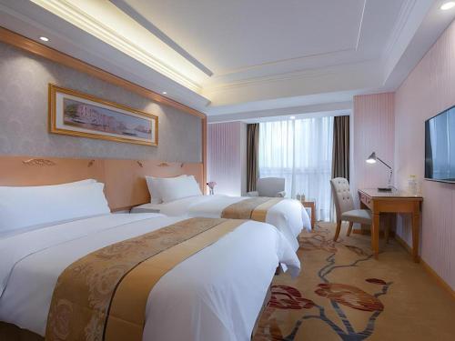a hotel room with two beds and a desk at Vienna Hotel Chengdu Chunxi Road Lijiatuo Metro Station in Chengdu