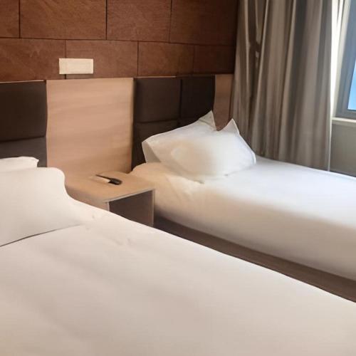 two beds sitting next to each other in a room at Shanghai Jiejia hotel in Shanghai
