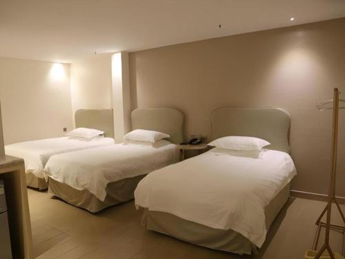 a hotel room with two beds with white sheets at Leisurely Hotel Shenzhen in Shenzhen