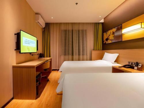 a hotel room with two beds and a desk and a television at IU Hotel Kunming Jinma Bijifang Joy City in Kunming