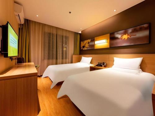 a hotel room with two beds and a flat screen tv at IU Hotel Kunming Jinma Bijifang Joy City in Kunming