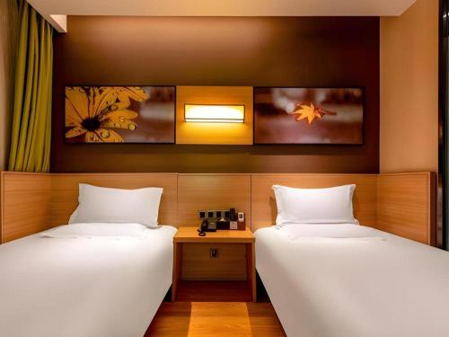 a room with two beds and a table at IU Hotel Kunming Jinma Bijifang Joy City in Kunming