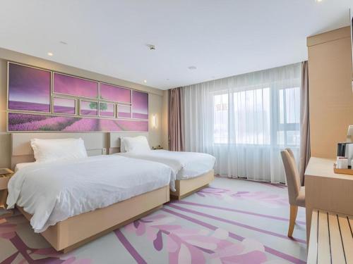 a hotel room with two beds and a desk at Lavande Hotels·Qingdao Wusi Square in Qingdao