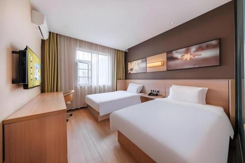 a hotel room with two beds and a television at IU Hotel Kunming Jinma Bijifang Joy City in Kunming