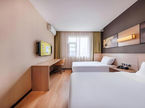 a hotel room with two beds and a desk at IU Hotel Kunming Jinma Bijifang Joy City in Kunming