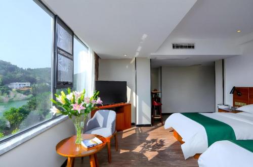 a room with two beds and a vase of flowers on a table at Immersing Hotel Guilin Two Rivers and Four Lakes Dongxi Alley in Guilin