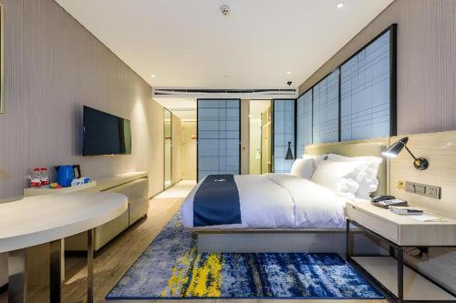 ein Schlafzimmer mit einem Bett, einem Schreibtisch und einem Fernseher in der Unterkunft Echarm Hotel Nanning Baisha Avenue Tingjiang Interchange BBK in Nanning
