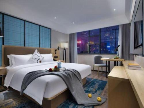 a bedroom with a large white bed and a desk at Echarm Hotel Jingjiang Bus Passenger Station Fanggu Street in Jingjiang