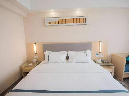 a bedroom with a large white bed with two tables at City Comfort Inn Shantou Daxue Road in Shantou