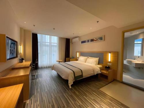 a hotel room with a large bed and a mirror at City Comfort Inn Deyang Shifang Yonghu Park in Deyang