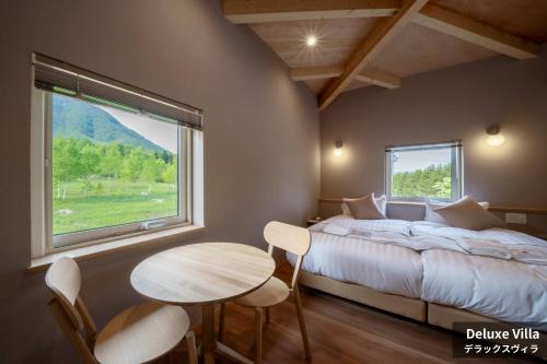 a bedroom with a bed and a table and a window at Rusutsu Hills CENTRO in Rusutsu