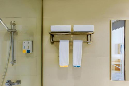 ein Bad mit drei an der Wand hängenden Handtüchern in der Unterkunft City Comfort Inn Xinyu Laodong Bei Road in Xinyu