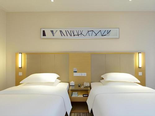 two beds in a hotel room with white pillows at City Comfort Inn Tongren High-speed Railway Station in Tongren