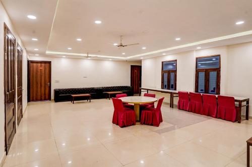 a living room with a table and red chairs at Hotel O Golden Palace in Noida