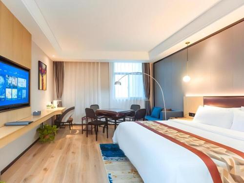 a hotel room with a large bed and a table at Gya Hotel Yangzhou Economic Development Zone Yangzijiang Nan Road Gaomin Temple in Yangzhou
