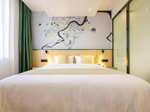 a bedroom with a large white bed with a map on the wall at Vatica Hotel Haikou Jinniuling Park Haizhiyuan in Haikou