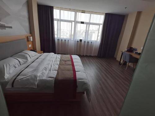 a bedroom with a large bed and a desk and window at Thank Inn Hotel Jiangsu Wuxi High-Tech Zone Ruigang Pedestrian Street in Wuxi