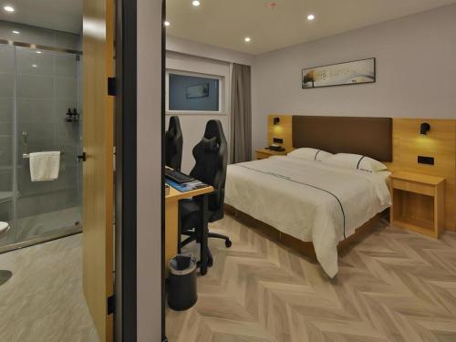 a bedroom with a bed and a desk and a shower at GreenTree Esports Hotel Qingdao Licang District Wanda in Qingdao