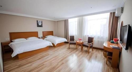 a hotel room with two beds and a desk at GreenTree Inn Dalian Jinzhou District Railway Station Ansheng Plaza in Dalian