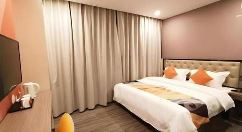 a bedroom with a large bed with orange pillows at Shell Hotel Shanghai Jinshan Wanda Plaza in Nanhui