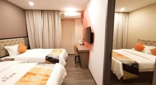 a hotel room with two beds and a desk at Shell Hotel Shanghai Jinshan Wanda Plaza in Nanhui