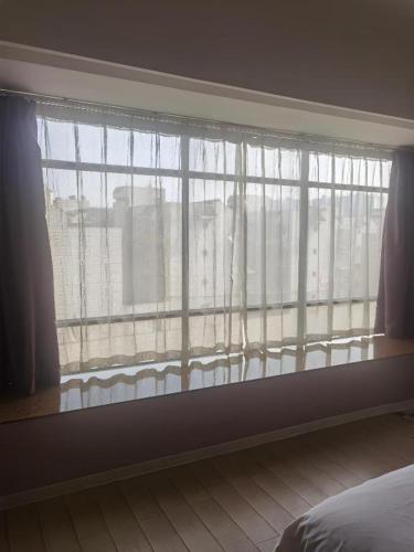 a bedroom with a large window with white curtains at Borrman Hotel Liuzhou High-Speed Railway Station in Liuzhou