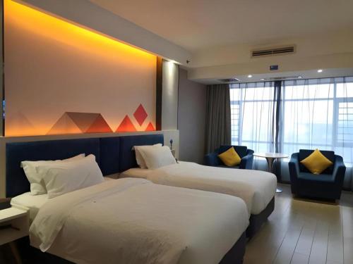 a hotel room with two beds and a chair at Borrman Hotel Liuzhou High-Speed Railway Station in Liuzhou