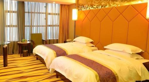 two beds in a hotel room with orange walls at VX Hotel Chengdu Jiaolong Port Haibin in Chengdu