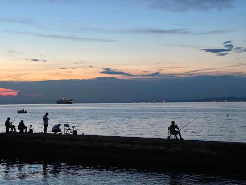 a group of people fishing on a dock in the water at 4 Roses Residence in Sečovlje