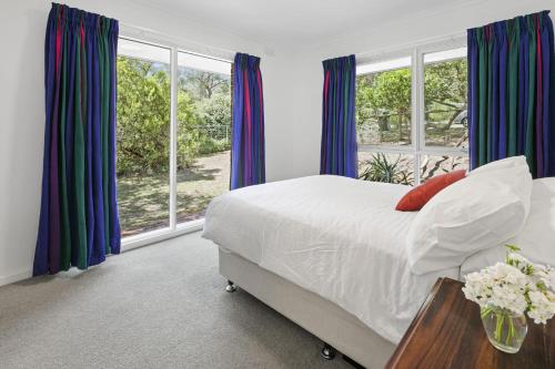 a bedroom with a large bed with blue curtains at Blairgowrie Beach Bungalow - Pet & Value Stay in Blairgowrie