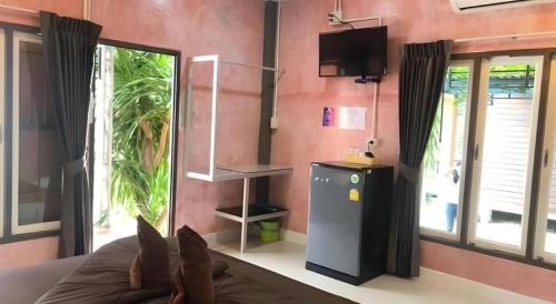 a room with a tv and a couch and a window at Kidthuengpark in Si Racha