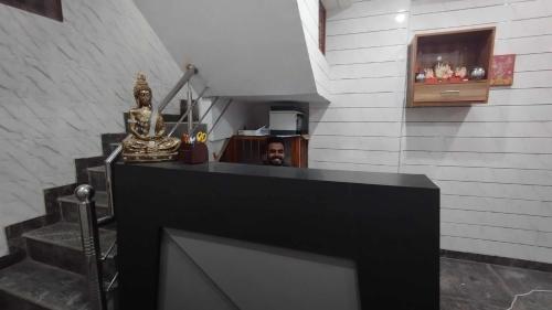 un hombre sentado en un mostrador en una habitación con escaleras en Hotel O Keshav Guest House, en Nueva Delhi
