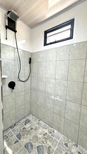 a bathroom with a shower with a window and a shower coil at Serenity Rooms Arenal in Guayabal