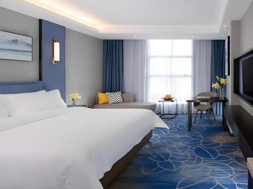 a bedroom with a large bed and a living room at Vienna Hotel Guangdong Foshan Yihuanlishui in Foshan