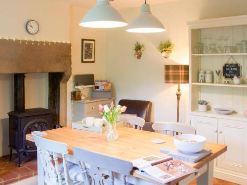 a dining room with a table and a fireplace at Penny Cottage in Bonsall