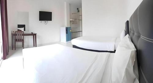 a white room with a bed and a desk at Niwtara Place Lom Sak Hotel in Phetchabun