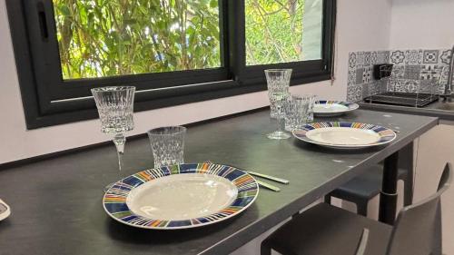 a table with plates and glasses on top of it at Grand logement 2 en 1 à Boucan Canot Plage in Saint-Gilles les Bains