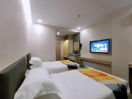 a hotel room with two beds and a flat screen tv at Shell Hotel Wuxi Huishan District Chang'an Town in Wuxi
