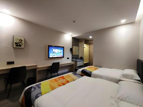 a hotel room with two beds and a television at Shell Hotel Wuxi Huishan District Chang'an Town in Wuxi
