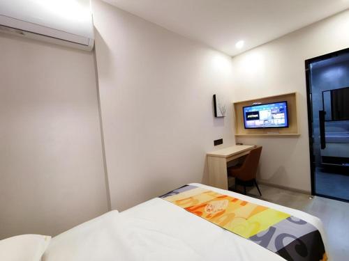 a bedroom with a bed and a desk and a tv at Shell Hotel Wuxi Huishan District Chang'an Town in Wuxi
